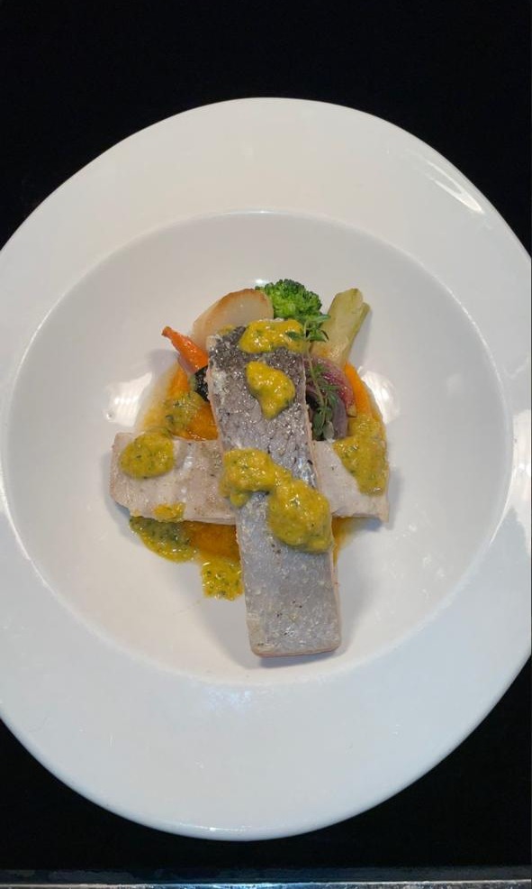Plated fish fillets with herb and citrus sauce, broccoli and roasted vegetables