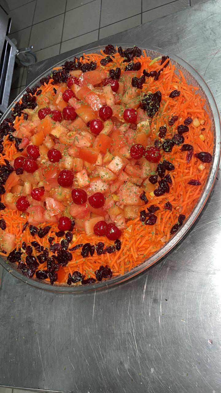 Platter of carrot salad with diced tomato, cranberries, cherries and fresh herbs