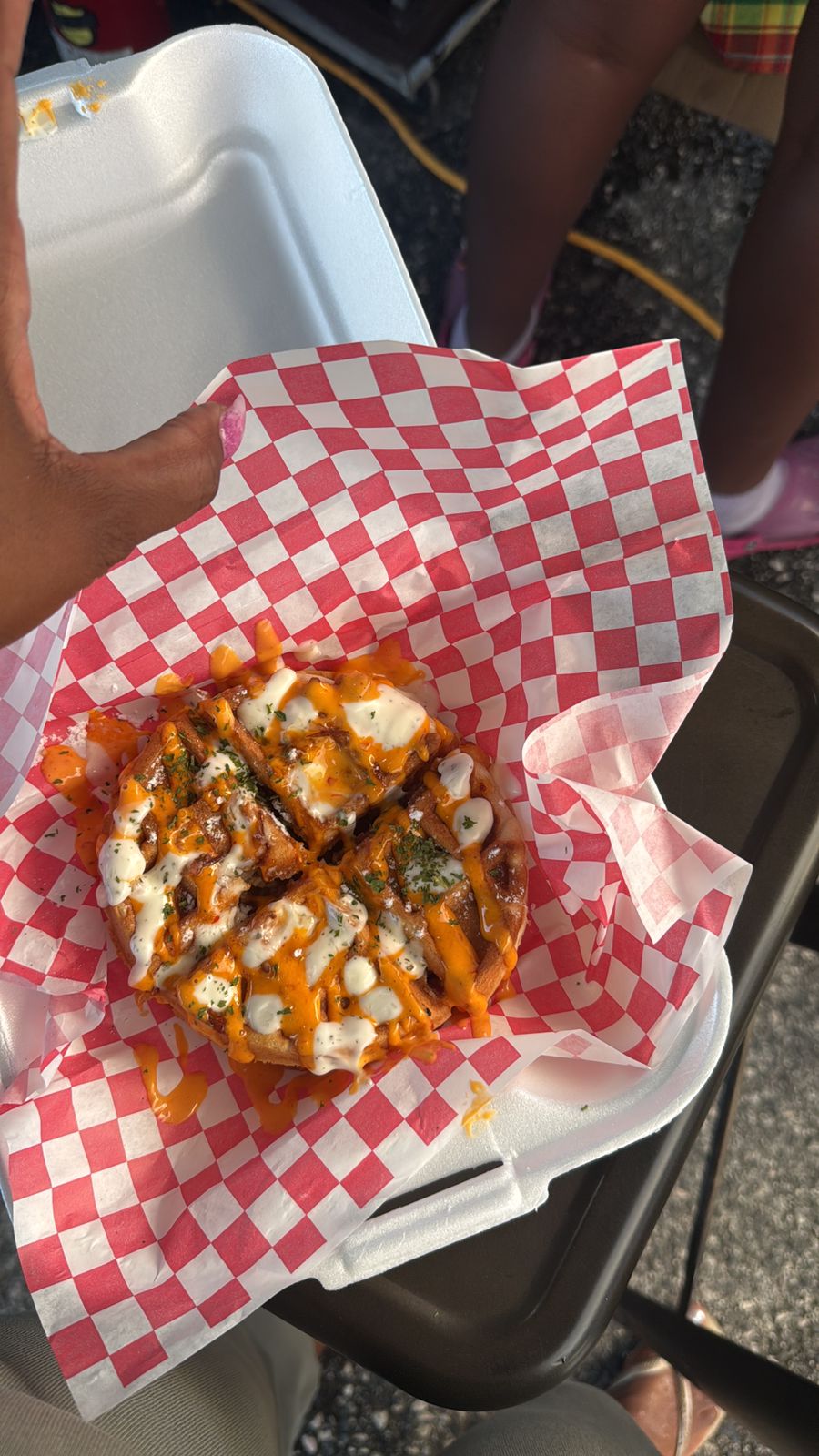 Savoury stuffed waffle drizzled with cheese sauce and garlic aioli on checkered paper
